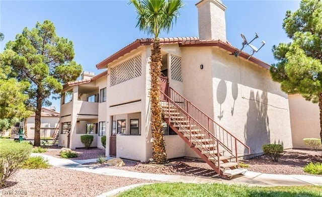 805 Rock Springs Dr Unit 101, Las Vegas, NV 89128 - rear view of house with stairway, stucco siding, and a chimney