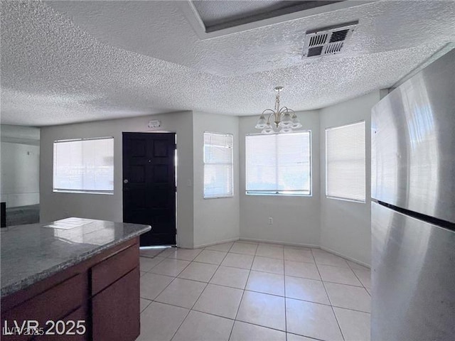 805 Rock Springs Dr Unit 101, Las Vegas, NV 89128 - unfurnished dining area featuring a chandelier, light tile patterned floors, and a textured ceiling