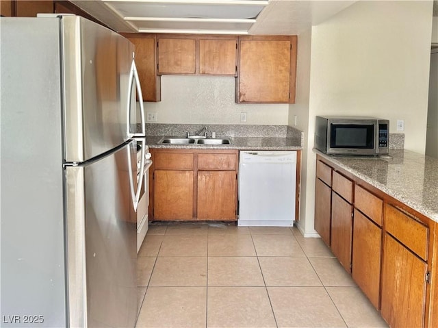 805 Rock Springs Dr Unit 101, Las Vegas, NV 89128 - kitchen featuring freestanding refrigerator, dishwasher, light tile patterned floors, stainless steel microwave, and brown cabinetry