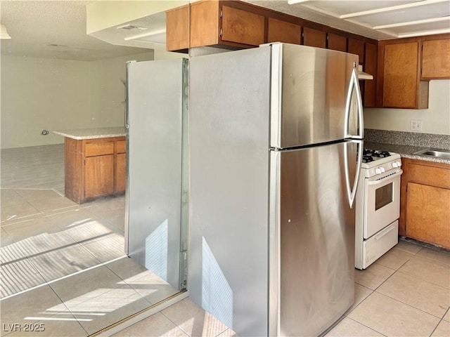 805 Rock Springs Dr Unit 101, Las Vegas, NV 89128 - kitchen with light tile patterned flooring, white range with gas stovetop, and brown cabinetry