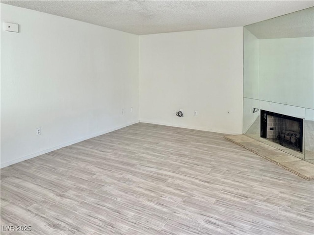 805 Rock Springs Dr Unit 101, Las Vegas, NV 89128 - unfurnished living room with a fireplace, a textured ceiling, and light wood-style flooring