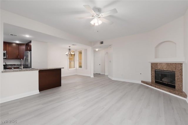 1609 Hills Of Red Dr Unit 104, Las Vegas, NV 89128 - unfurnished living room with light wood-style floors, a chandelier, a fireplace, and a ceiling fan