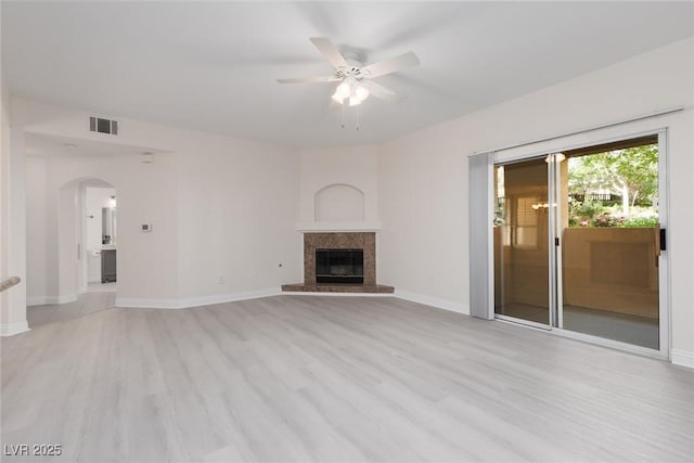 1609 Hills Of Red Dr Unit 104, Las Vegas, NV 89128 - unfurnished living room featuring ceiling fan, light wood-type flooring, arched walkways, and a glass covered fireplace