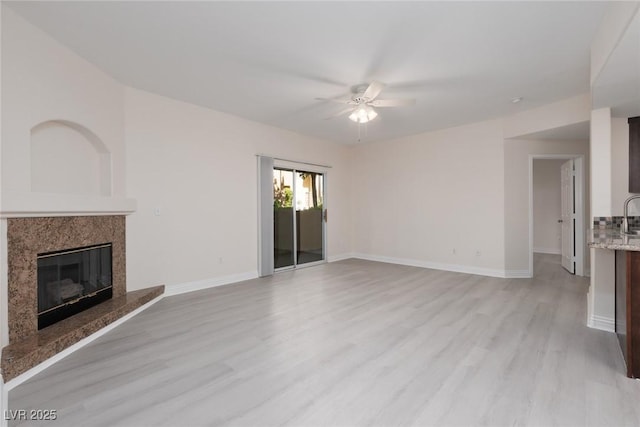 1609 Hills Of Red Dr Unit 104, Las Vegas, NV 89128 - unfurnished living room featuring ceiling fan, light wood-style floors, and a fireplace