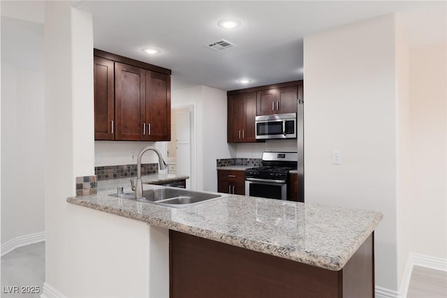 1609 Hills Of Red Dr Unit 104, Las Vegas, NV 89128 - kitchen with stainless steel appliances, dark brown cabinets, a peninsula, recessed lighting, and light stone counters