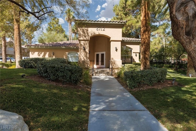 1609 Hills Of Red Dr Unit 104, Las Vegas, NV 89128 - view of front facade with french doors, a tiled roof, stucco siding, and a front lawn