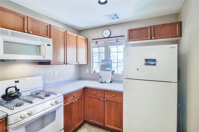 9068 Alluring Ave, Las Vegas, NV 89149 - kitchen featuring white appliances, light countertops, brown cabinetry, and light tile patterned floors
