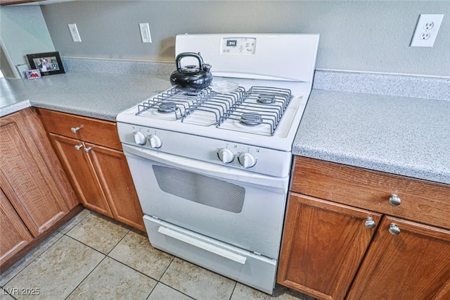 9068 Alluring Ave, Las Vegas, NV 89149 - kitchen featuring white gas range, brown cabinetry, and light tile patterned flooring