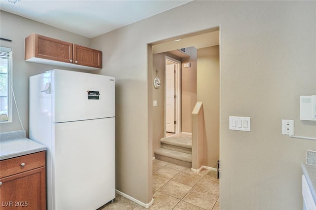 9068 Alluring Ave, Las Vegas, NV 89149 - kitchen with freestanding refrigerator, brown cabinets, light countertops, and light tile patterned floors