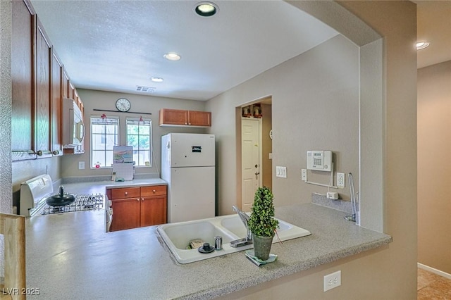 9068 Alluring Ave, Las Vegas, NV 89149 - kitchen with white appliances, a peninsula, recessed lighting, light countertops, and brown cabinets
