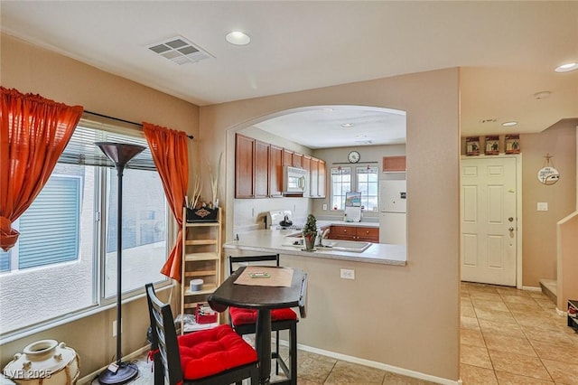 9068 Alluring Ave, Las Vegas, NV 89149 - kitchen featuring white appliances, arched walkways, light countertops, light tile patterned floors, and recessed lighting