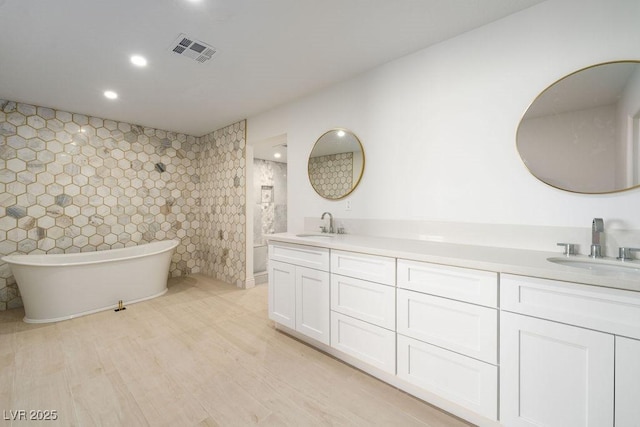 714 Lacy Ln, Las Vegas, NV 89107 - bathroom featuring double vanity, a freestanding bath, recessed lighting, and wood finished floors