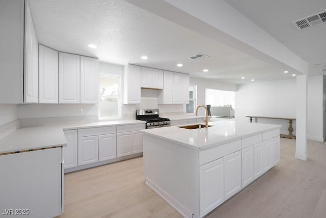 714 Lacy Ln, Las Vegas, NV 89107 - kitchen featuring gas stove, light wood-style floors, white cabinets, an island with sink, and recessed lighting