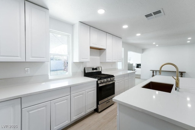 714 Lacy Ln, Las Vegas, NV 89107 - kitchen with gas range, white cabinets, recessed lighting, light wood-type flooring, and a textured ceiling