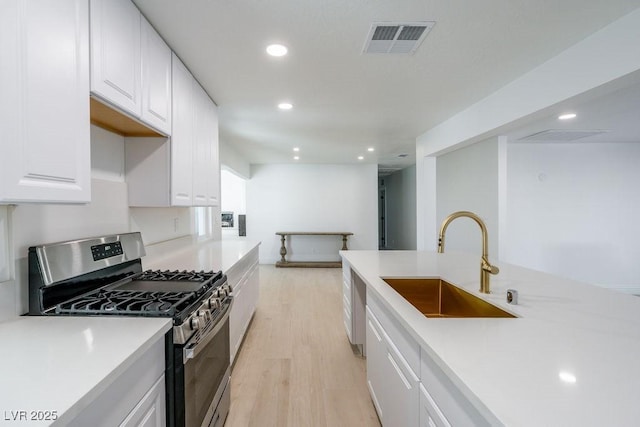 714 Lacy Ln, Las Vegas, NV 89107 - kitchen with stainless steel range with gas stovetop, light wood-style floors, recessed lighting, light countertops, and white cabinets