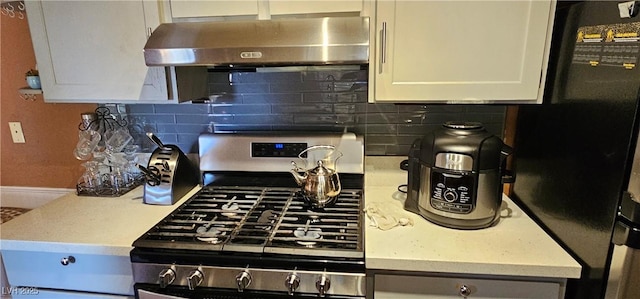 4232 Brockton Green Ct, Las Vegas, NV 89110 - kitchen featuring gas stove, freestanding refrigerator, range hood, decorative backsplash, and white cabinetry
