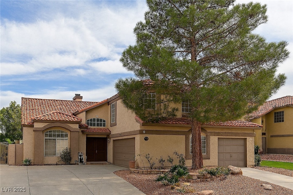 32 Stone Cress Dr, Henderson, NV 89074 - mediterranean / spanish-style home with concrete driveway, a tiled roof, stucco siding, a chimney, and an attached garage