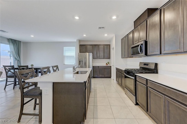 4133 Golden Fleece Ave, Las Vegas, NV 89141 - kitchen with appliances with stainless steel finishes, a breakfast bar area, dark brown cabinets, recessed lighting, and an island with sink