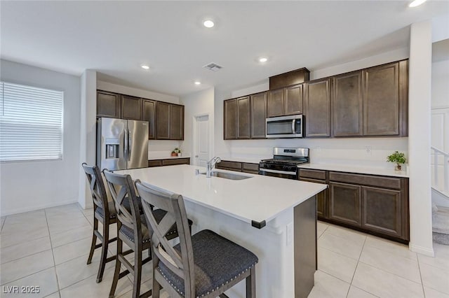 4133 Golden Fleece Ave, Las Vegas, NV 89141 - kitchen with appliances with stainless steel finishes, light tile patterned flooring, a kitchen bar, dark brown cabinets, and an island with sink