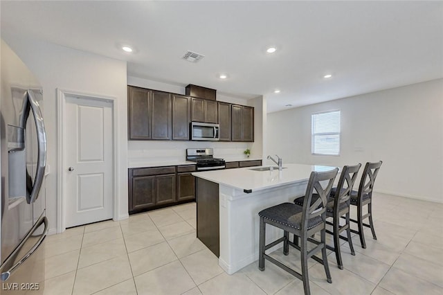 4133 Golden Fleece Ave, Las Vegas, NV 89141 - kitchen with appliances with stainless steel finishes, a kitchen bar, dark brown cabinets, a kitchen island with sink, and light countertops