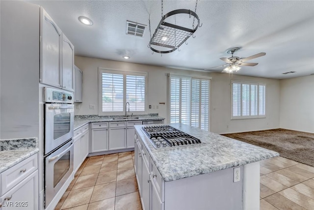 208 Glendon St, Henderson, NV 89074 - kitchen with healthy amount of natural light, light tile patterned flooring, a kitchen island, appliances with stainless steel finishes, and a textured ceiling