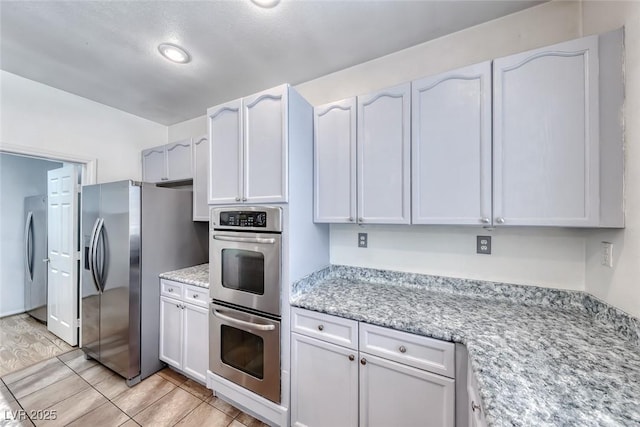 208 Glendon St, Henderson, NV 89074 - kitchen featuring appliances with stainless steel finishes, white cabinetry, light stone countertops, and light tile patterned flooring