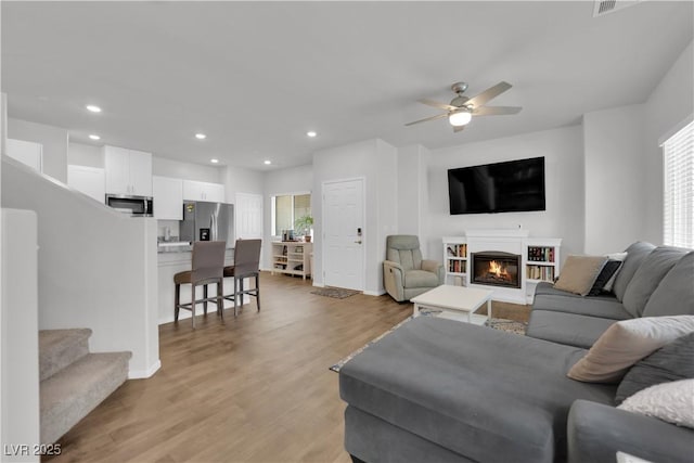 4650 Blaise Ave Unit 102, North Las Vegas, NV 89084 - living area featuring ceiling fan, light wood-style floors, recessed lighting, a glass covered fireplace, and stairs