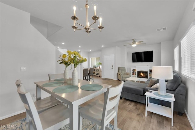 4650 Blaise Ave Unit 102, North Las Vegas, NV 89084 - dining room featuring light wood finished floors, a lit fireplace, a ceiling fan, a chandelier, and recessed lighting