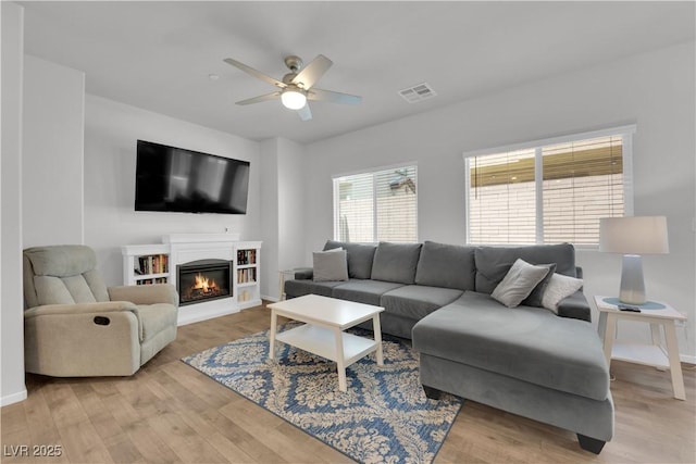 4650 Blaise Ave Unit 102, North Las Vegas, NV 89084 - living area featuring a ceiling fan, light wood-style floors, and a glass covered fireplace