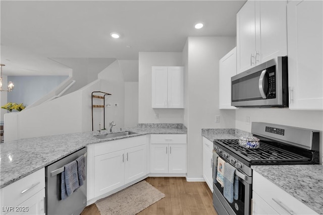 4650 Blaise Ave Unit 102, North Las Vegas, NV 89084 - kitchen with appliances with stainless steel finishes, light wood-style floors, white cabinetry, light stone countertops, and a chandelier