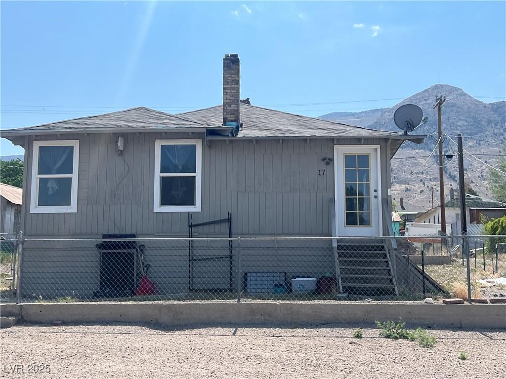 17 Second St, Mcgill, NV 89318 - rear view of property with roof with shingles, a fenced front yard, a chimney, and a mountain view