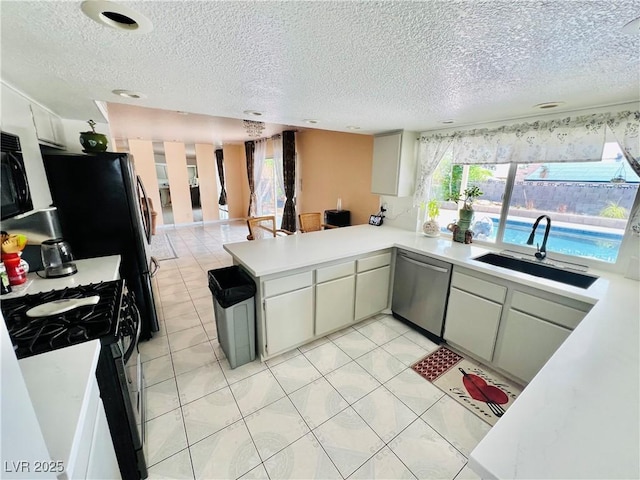 421 Courtney Ln, Las Vegas, NV 89107 - kitchen featuring stainless steel dishwasher, black gas stove, a peninsula, a textured ceiling, and light countertops