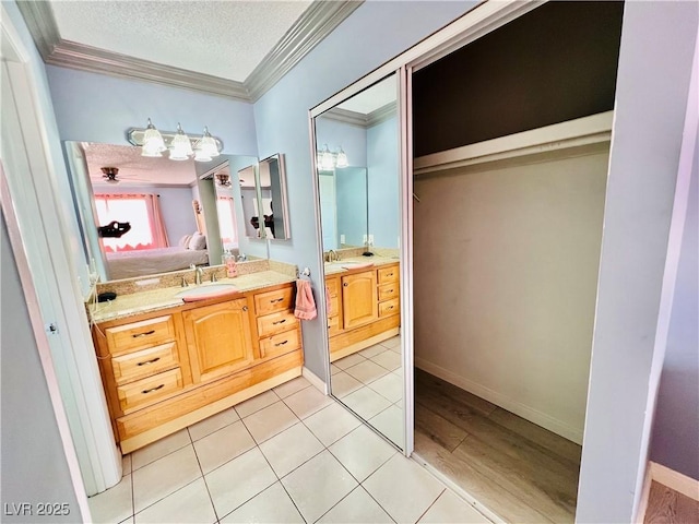 421 Courtney Ln, Las Vegas, NV 89107 - ensuite bathroom featuring ornamental molding, two vanities, a textured ceiling, and tile patterned floors
