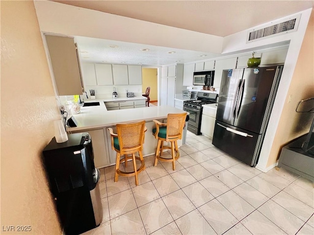 421 Courtney Ln, Las Vegas, NV 89107 - kitchen featuring appliances with stainless steel finishes, a peninsula, light countertops, light tile patterned flooring, and a breakfast bar