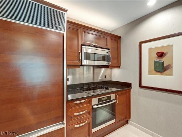 125 E Harmon Ave Unit 220, Las Vegas, NV 89109 - kitchen featuring stainless steel appliances, dark countertops, brown cabinets, light tile patterned flooring, and recessed lighting