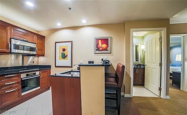 125 E Harmon Ave Unit 220, Las Vegas, NV 89109 - kitchen with stainless steel appliances, dark countertops, recessed lighting, a breakfast bar area, and light tile patterned flooring