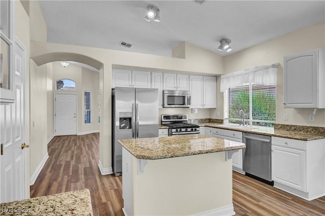 3520 Round Valley Way, Las Vegas, NV 89129 - kitchen with arched walkways, light stone countertops, appliances with stainless steel finishes, wood finished floors, and a center island