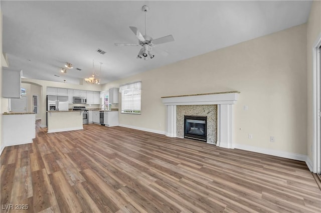 3520 Round Valley Way, Las Vegas, NV 89129 - unfurnished living room featuring ceiling fan, light wood-style floors, a glass covered fireplace, and a chandelier
