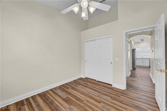 3520 Round Valley Way, Las Vegas, NV 89129 - unfurnished bedroom with wood finished floors, arched walkways, a closet, freestanding refrigerator, and a high ceiling