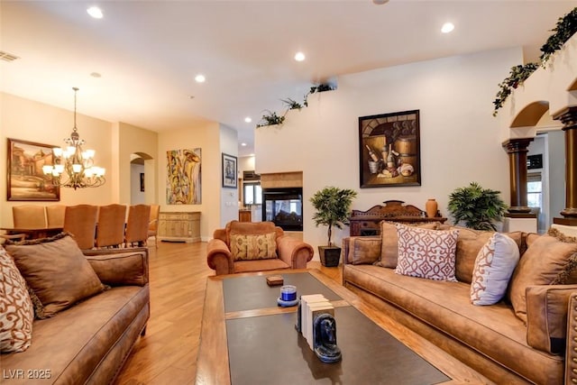 8465 Picket Ridge Ct, Las Vegas, NV 89143 - living room featuring arched walkways, light wood-type flooring, recessed lighting, a chandelier, and decorative columns