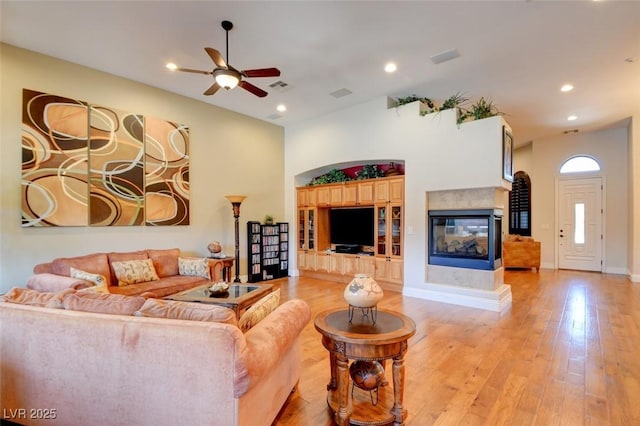 8465 Picket Ridge Ct, Las Vegas, NV 89143 - living room featuring a multi sided fireplace, ceiling fan, light wood finished floors, and recessed lighting