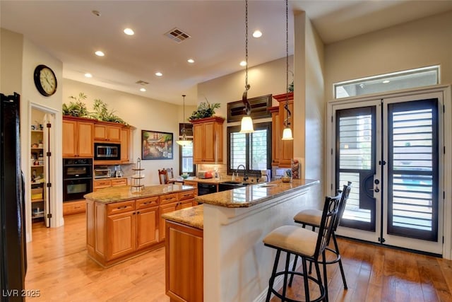 8465 Picket Ridge Ct, Las Vegas, NV 89143 - kitchen with light wood-style flooring, a breakfast bar area, a kitchen island, a peninsula, and french doors