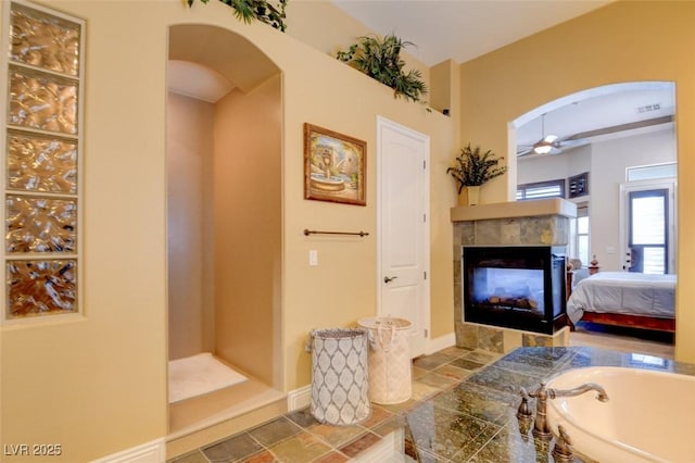 8465 Picket Ridge Ct, Las Vegas, NV 89143 - ensuite bathroom featuring ceiling fan, a fireplace, and a bath