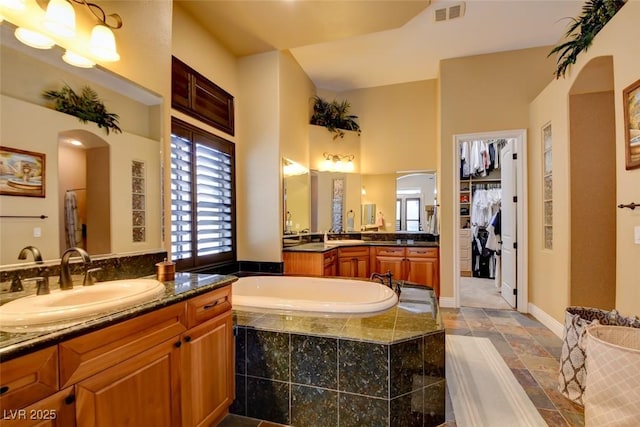 8465 Picket Ridge Ct, Las Vegas, NV 89143 - bathroom featuring vanity, a garden tub, and stone finish floors