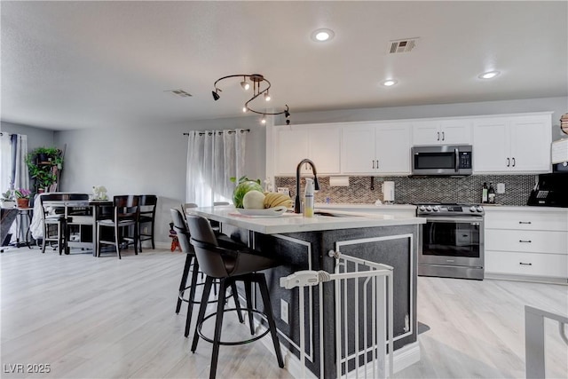 441 Groft Way, Henderson, NV 89015 - kitchen with stainless steel appliances, decorative backsplash, light wood finished floors, a kitchen bar, and recessed lighting