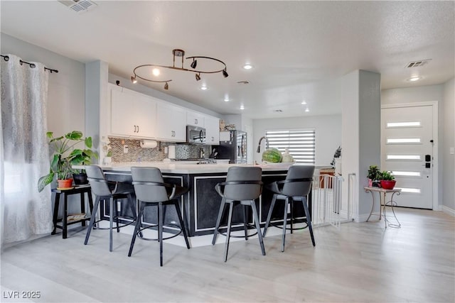 441 Groft Way, Henderson, NV 89015 - kitchen with a breakfast bar area, decorative backsplash, light countertops, white cabinetry, and a peninsula