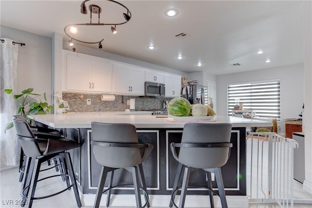 441 Groft Way, Henderson, NV 89015 - kitchen with light countertops, backsplash, white cabinets, a peninsula, and a kitchen breakfast bar