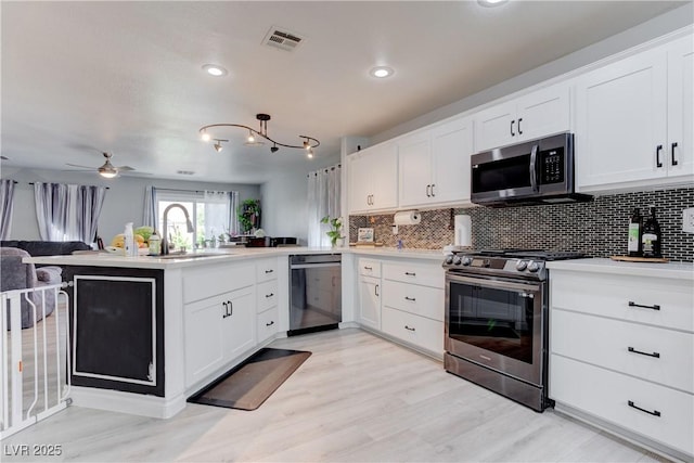 441 Groft Way, Henderson, NV 89015 - kitchen with stainless steel appliances, a peninsula, decorative backsplash, light wood finished floors, and recessed lighting