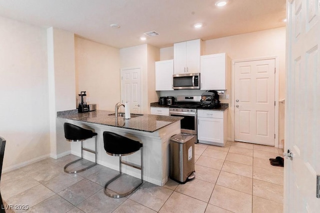 7331 Sunray Point St, North Las Vegas, NV 89084 - kitchen featuring stainless steel appliances, dark stone countertops, white cabinetry, recessed lighting, and a breakfast bar