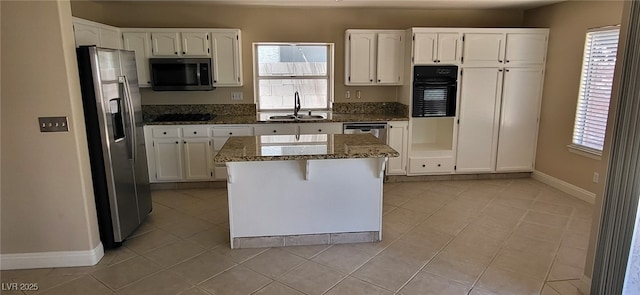 9204 Vosburgh Dr, Las Vegas, NV 89117 - kitchen featuring stainless steel appliances, dark stone counters, white cabinets, and light tile patterned floors